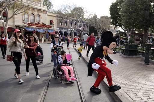 Visitors follow Mickey Mouse for photos at Disneyland, January 22, 2015, in Anaheim, Calif