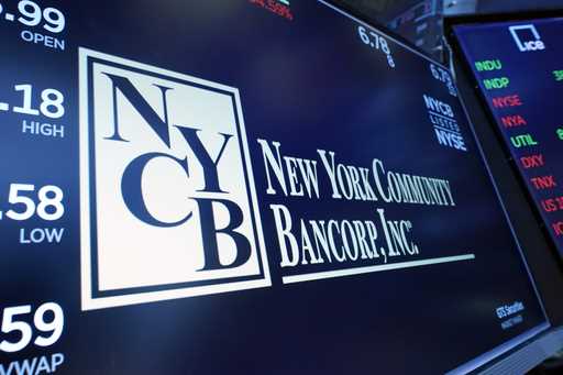 The logo for New York Community Bancorp is displayed above a trading post on the floor of the New Y…
