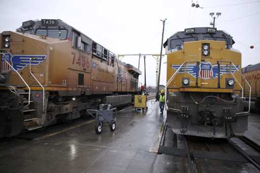 A Union Pacific worker walks between two locomotives that are being serviced in a railyard in Counc…