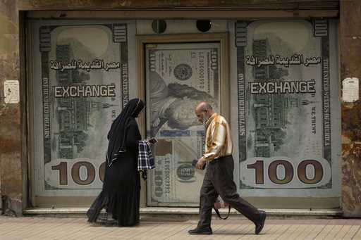 Egyptians walk past an exchange office in Cairo, Egypt, Wednesday, March 6, 2024