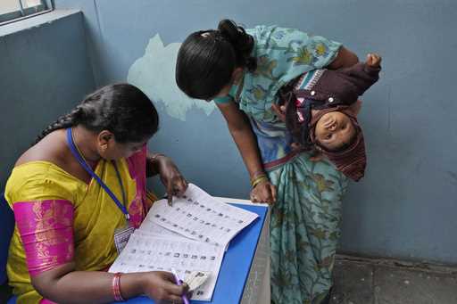 A woman checks for her name before casting her vote at a polling station during the Telangana state…
