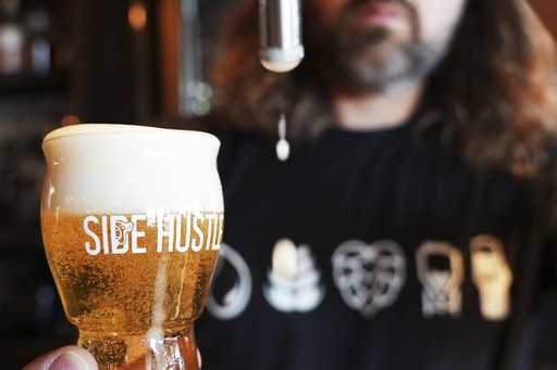Mitchell Dougherty, the brewmaster at Side Hustle Brews and Spirts, pours a pint of beer at their b…