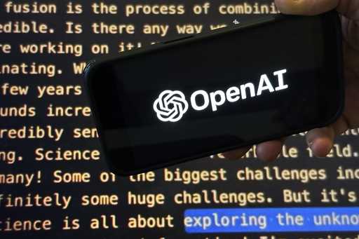 File - The OpenAI logo appears on a mobile phone in front of a screen showing part of the company w…