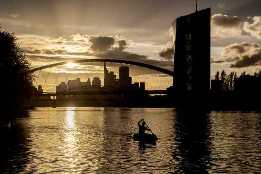 A man rows along the Main river, with the European Central Bank, right in background, in Frankfurt,…