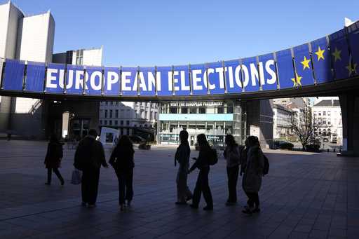 A group stands under an election banner outside the European Parliament in Brussels on April 29, 20…