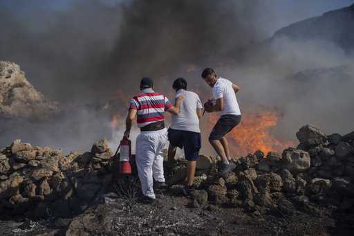 Local residents try to extinguish a fire, near the seaside resort of Lindos, on the Aegean Sea isla…