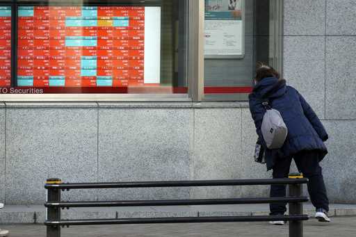 A person looks at an electronic stock board showing Japan's Nikkei 225 index at a securities firm i…