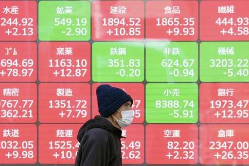 A person walks in front of an electronic stock board showing Japan's sector Indices at a securities…