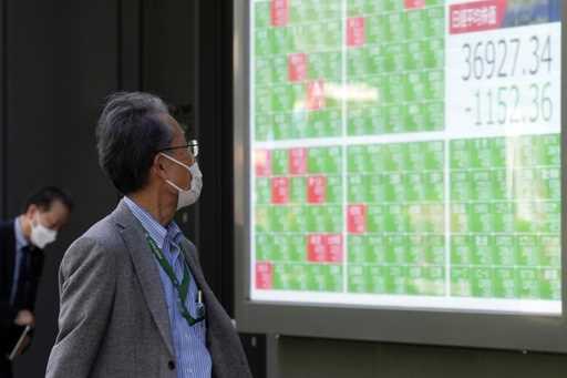 A person looks at an electronic stock board showing Japan's Nikkei 225 index at a securities firm i…
