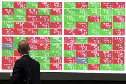 A person looks at an electronic stock board showing Japan's Nikkei 225 index at a securities firm i…