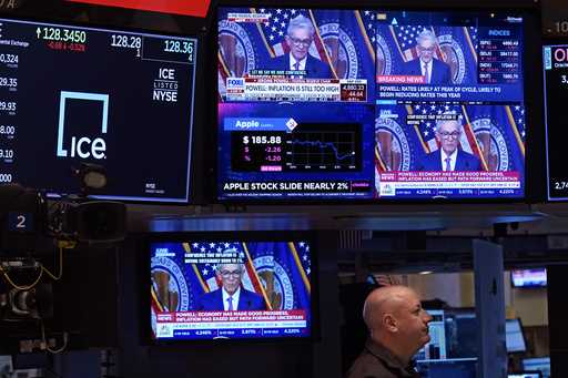 Television screens on the floor of the New York Stock Exchange show the news conference of Federal …