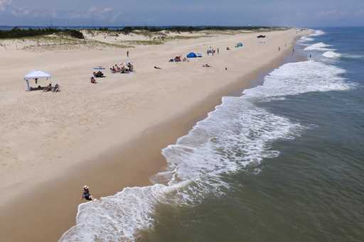 Waves crash near a beachgoer on July 13, 2022, in Rehoboth Beach, Del