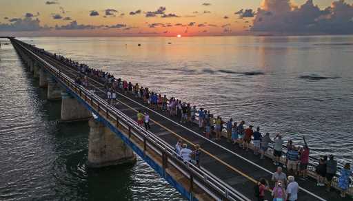 In this aerial photo provided by the Florida Keys News Bureau, attendees watch and toast the sunset…