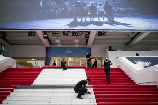 Festival workers lay the red carpet at the Palais des Festivals on opening day of the 77th internat…