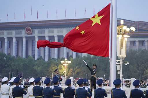 In this photo released by Xinhua News Agency, a member of the Chinese honor guard unfurls the Chine…