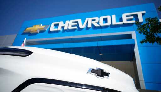 The company logo shines off the nose of an unsold 2022 Bolt electric vehicle on display in front of…