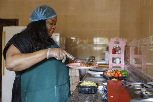 Anita Akpeere, who uses her mobile phone to run her business, prepares food at her restaurant in Ac…