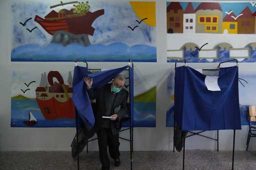 A man leaves the voting booth as he's votes at a polling station in Athens, Greece, Sunday, May 21,…