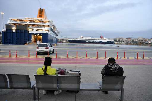 Two men sit on a bench as the ferries are docked at the port of Piraeus near Athens, during a strik…