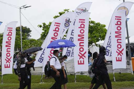 High school students walk past ExxonMobil flags as they arrive to a job fair at the University of G…