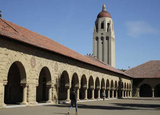 People walk on the Stanford University campus beneath Hoover Tower in Stanford, Calif