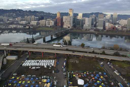In this aerial photo, tents housing people experiencing homelessness are set up on a vacant parking…