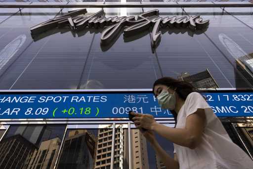 A pedestrian passes by the Hong Kong Stock Exchange electronic screen in Hong Kong, Friday, June 2,…