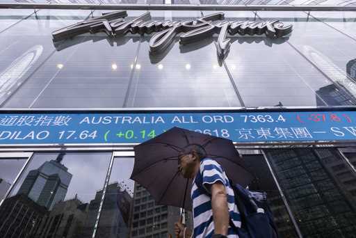 A pedestrian passes by the electronic screen of the Hong Kong Stock Exchange in Hong Kong, Tuesday,…