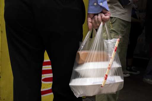 A pedestrian carries takeaway food plastic bag in Hong Kong, Thursday, February 21, 2024