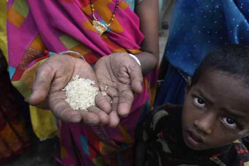 A woman from an impoverished family shows the sample of rice which she received under a government …