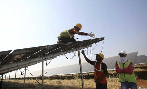 Workers install solar panels at the Pavagada Solar Park 175 Kilometers north of Bangalore, India, M…