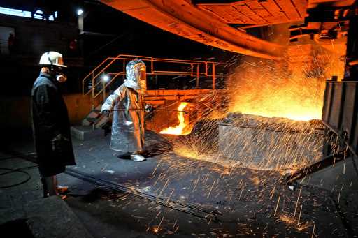 A worker in a protective suit pokes a metal rod to tap slag from a smelting furnace at PT Vale Indo…