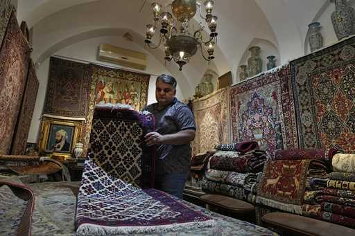 Iranian carpet shop owner Ali Faez works at his shop at the traditional bazaar of the city of Kasha…