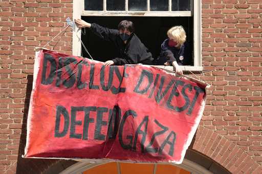 Activists hang a placard from a window of an upper floor of a building at Rhode Island School of De…