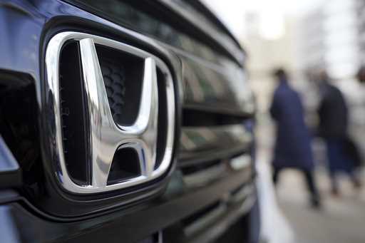 People walk near the logo of Honda Motor Company at a showroom on February 8, 2022, in Tokyo