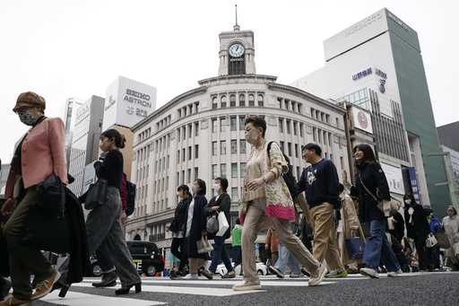 People walk across a pedestrian crossing in Ginza shopping district in Tokyo on March 31, 2023