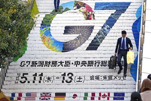 People goes down station stairs featuring the logo of the G7 Finance Ministers and Central Bank Gov…