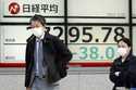 People walk in front of an electronic stock board showing Japan's Nikkei 225 index at a securities …