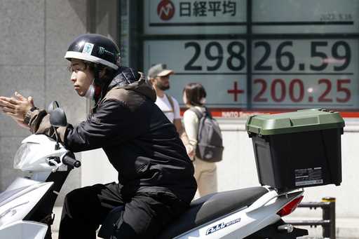 A person walks in front of an electronic stock board showing Japan's Nikkei 225 and New York Dow in…