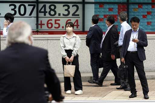 A person looks at an electronic stock board showing Japan's stock prices at a securities firm Wedne…