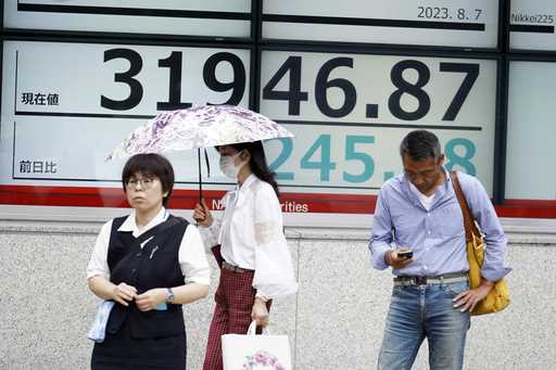 People stand in front of an electronic stock board showing Japan's Nikkei 225 index at a securities…
