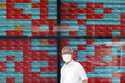 A person stands in front of an electronic stock board showing Japan's Nikkei 225 index at a securit…
