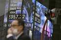 A person walks in front of an electronic stock board showing Japan's Stock Price index at a securit…