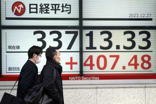 People walk in front of an electronic stock board showing Japan's Nikkei 225 index at a securities …
