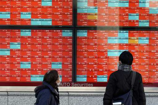 People look at an electronic stock board showing Japan's stock prices at a securities firm on Janua…