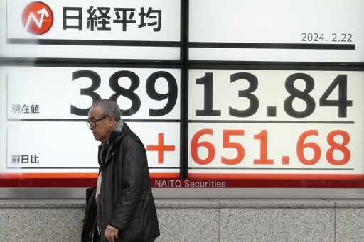 A person walks in front of an electronic stock board showing Japan's Nikkei 225 index at a securiti…