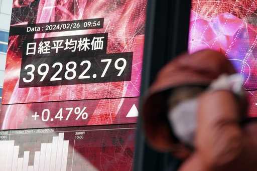 A person walks in front of an electronic stock board showing Japan's Nikkei 225 index at a securiti…