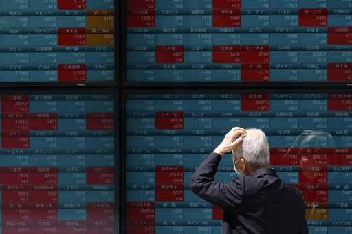 A person looks at an electronic stock board showing Japan's Nikkei 225 index at a securities firm T…