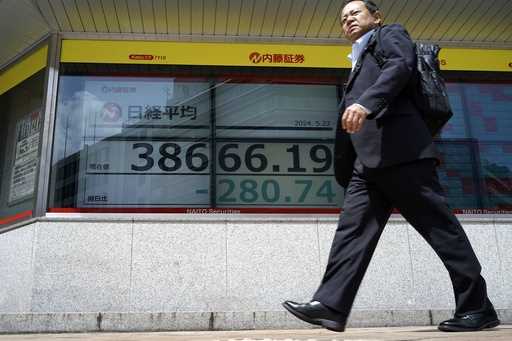 A person walks past an electronic stock board showing Japan's Nikkei 225 index, center, at a securi…