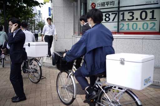 People pass in front of an electronic stock board showing Japan's Nikkei 225 index at a securities …